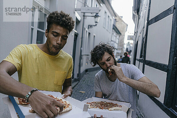 Zwei Freunde essen Pizza zum Mitnehmen in der Stadt