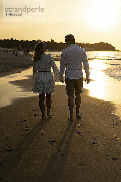 Freund und Freundin halten sich an den Händen  während sie ihre Freizeit am Strand verbringen