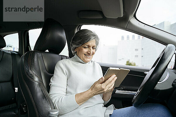 Lächelnde Frau benutzt Smartphone im Auto