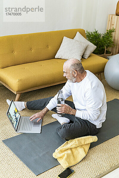 Älterer Mann schaut sich zu Hause Übungsanleitung über Laptop an