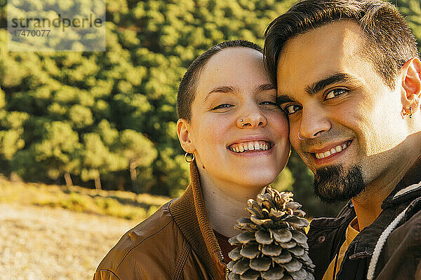 Lächelndes Paar mit Tannenzapfen auf dem Berg