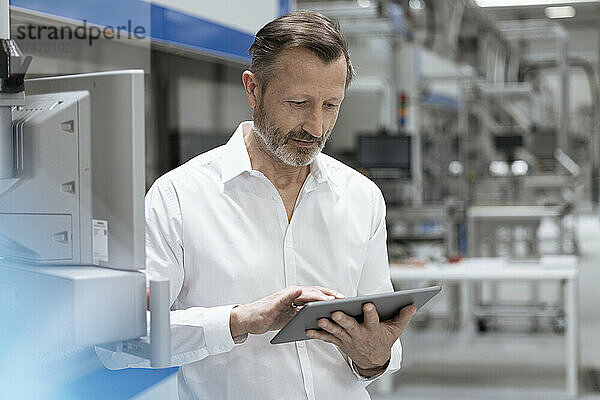 Männlicher Profi  der in der Fabrik an einem digitalen Tablet arbeitet