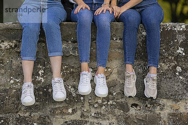 Freundinnen sitzen auf Stützmauer