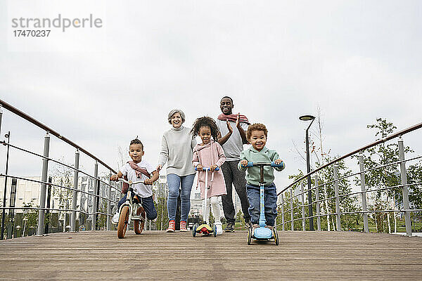 Kinder spielen mit Tretroller und Fahrrad auf der Brücke