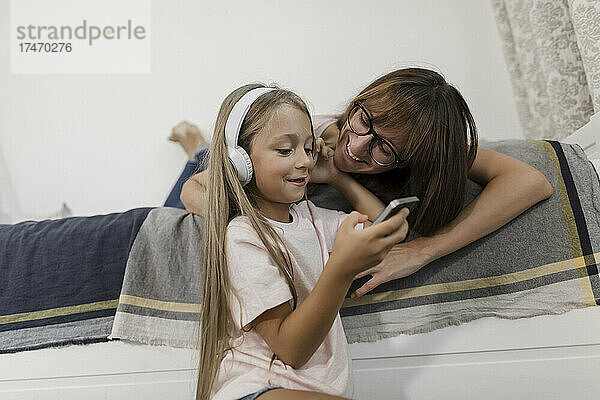 Mädchen hört Musik über Kopfhörer mit Frau zu Hause