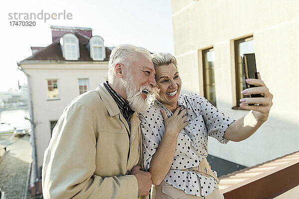 Glückliches Paar nimmt per Mobiltelefon an einem Videoanruf auf der Terrasse teil