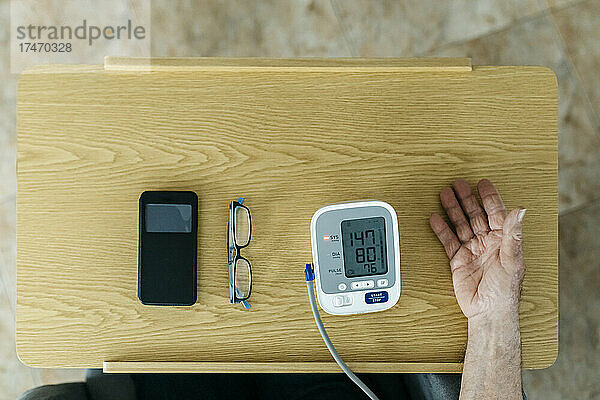 Mann überprüft zu Hause den Blutdruck auf dem Tisch