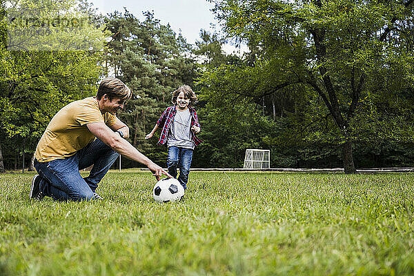 Familie spielt mit Fußball auf Rasen