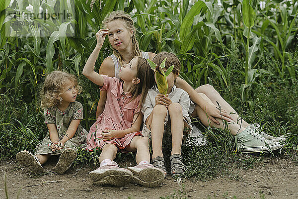 Mutter sitzt mit Sohn und Töchtern im Maisfeld