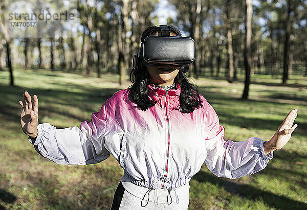 Frau mit Virtual-Reality-Headset gestikuliert im Park
