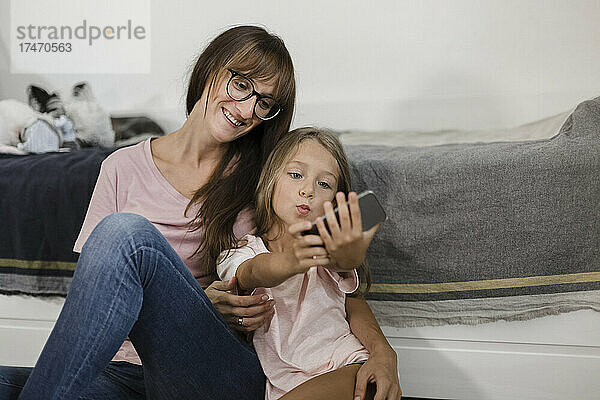 Mädchen macht zu Hause ein Selfie mit einer Frau über ihr Mobiltelefon