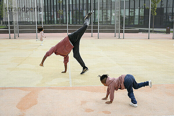 Sohn übt Handspring und schaut Vater auf dem Sportplatz an