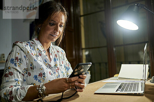Geschäftsfrau nutzt Smartphone und Laptop im Büro