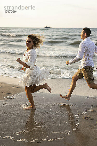 Freundin und Freund laufen am Strand am Meer