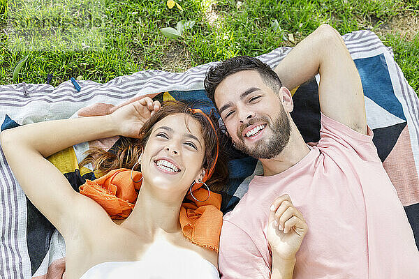 Lächelndes junges Paar liegt auf einer Picknickdecke