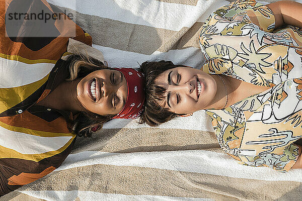 Smiling women lying on picnic blanket at beach