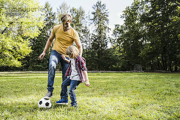 Vater und Sohn spielen im Park mit Fußball