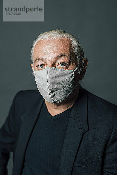 Reifer Mann mit schützender Gesichtsmaske vor grauem Hintergrund
