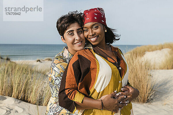 Liebevolles lesbisches Paar  das sich an einem sonnigen Tag am Strand umarmt
