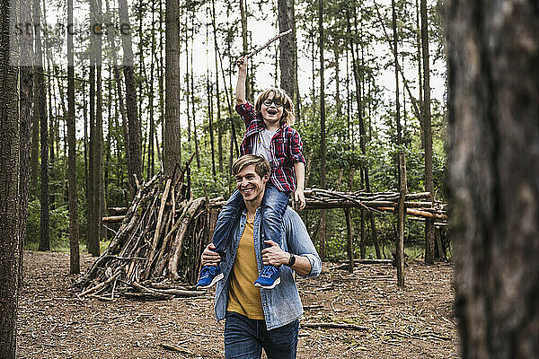 Glücklicher Vater trägt Sohn auf Schultern im Wald