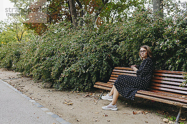 Lächelnde Frau sitzt auf einer Bank im öffentlichen Park