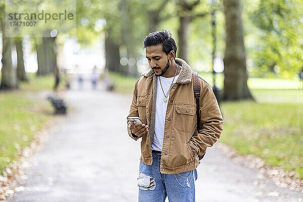 Junger Mann benutzt Smartphone im Park