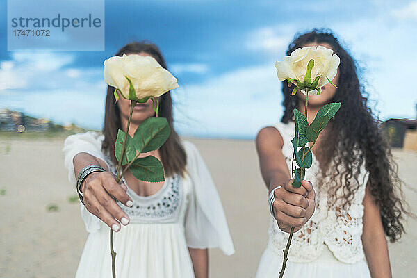 Lesbisches Paar hält Blumen am Strand