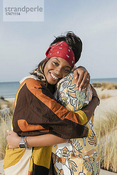 Glückliche Frau umarmt lesbische Freundin am Strand