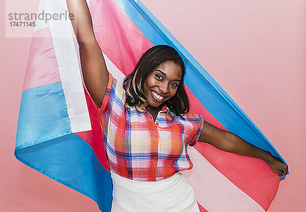 Glückliche Frau mit Transgender-Flagge vor rosa Hintergrund