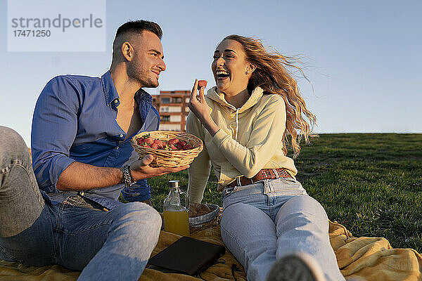 Fröhliche Freundin genießt Picknick mit Freund auf dem Hügel