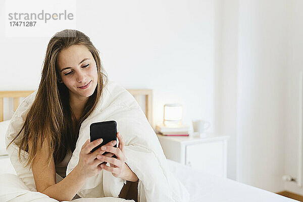 Lächelnde junge Frau mit braunen Haaren im Smart-N-Bett