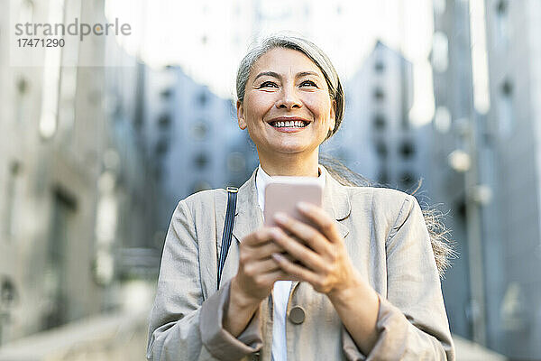 Glückliche Frau mit grauen Haaren  die ihr Mobiltelefon in der Hand hält