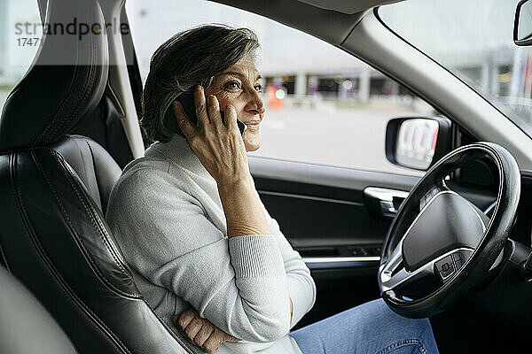 Frau spricht mit Smartphone  während sie im Auto sitzt