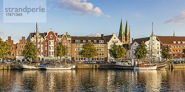 Deutschland  Schleswig-Holstein  Lübeck  Panoramablick auf Segelschiffe  die am Travekanal festmachen  mit historischen Stadthäusern im Hintergrund