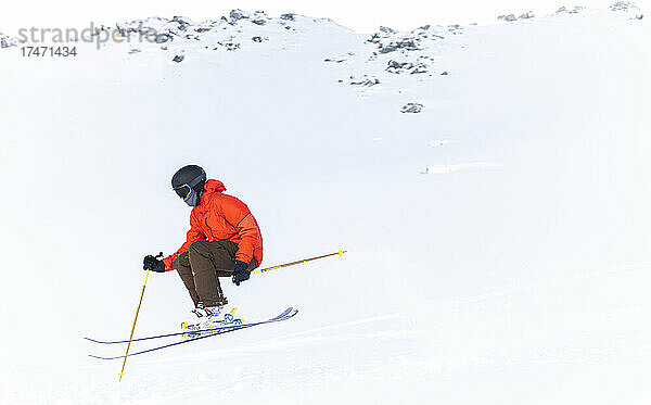 Mann in roter Jacke fährt auf schneebedecktem Berg Ski