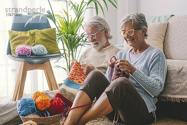 Älteres Paar strickt Wolle im Wohnzimmer