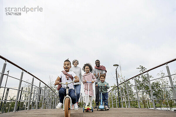 Kinder fahren mit Tretroller und Fahrrad auf der Brücke