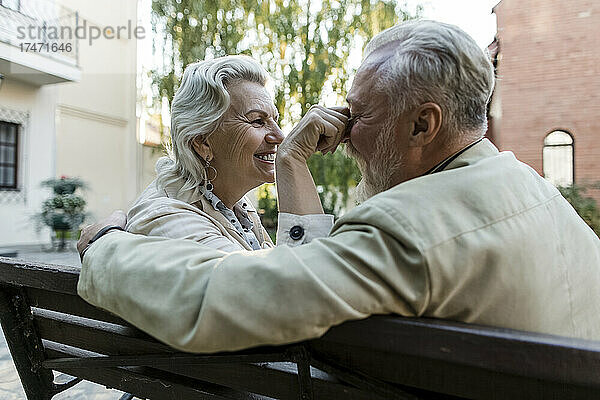Ältere Frau spielt mit Männernase auf Bank