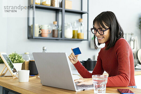 Geschäftsfrau hält Kreditkarte in der Hand und arbeitet zu Hause am Laptop