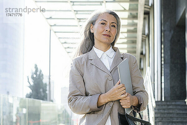 Reife Geschäftsfrau mit grauem Haar hält Laptop in der Hand
