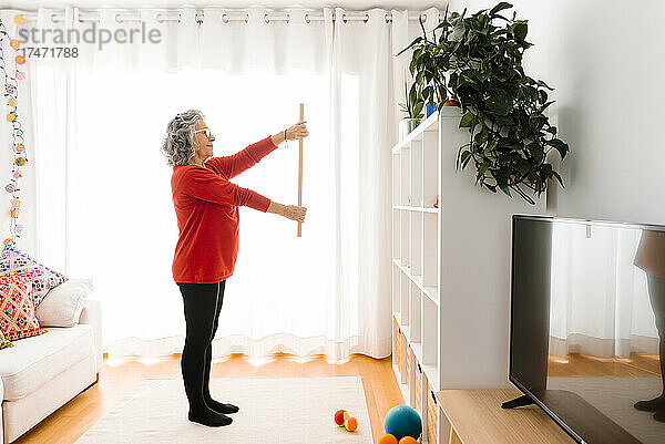 Ältere Frau trainiert zu Hause im Wohnzimmer