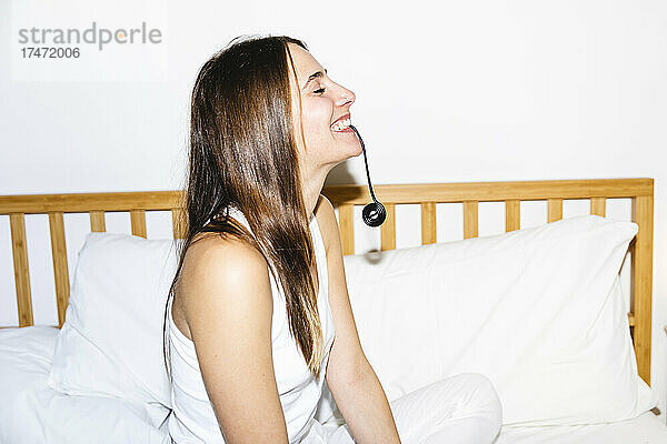 Glückliche junge Frau  die im Schlafzimmer Lakritzbonbons isst