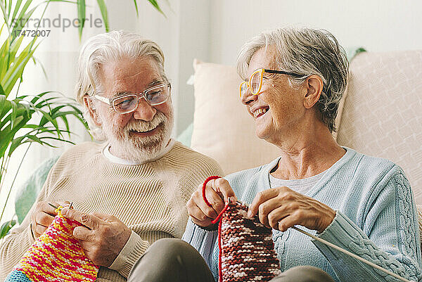 Lächelndes Paar strickt zu Hause Wolle mit Nadel