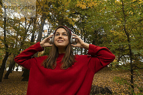 Lächelnde Frau mit Kopfhörern im Park