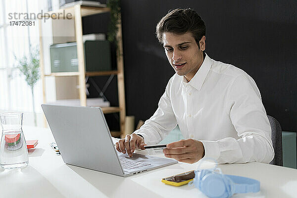 Geschäftsmann mit Kreditkarte tätigt Online-Einkäufe per Laptop im Büro