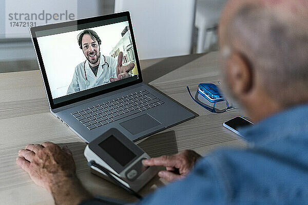 Arzt berät älteren Mann per Videoanruf auf Laptop