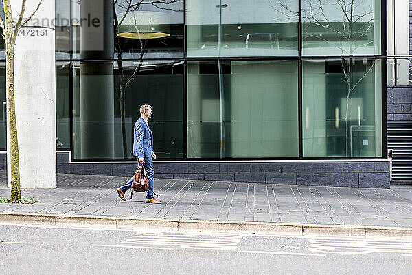Geschäftsmann trägt Rucksack beim Gehen auf Fußweg