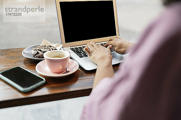 Frau benutzt Laptop auf Tisch im Café