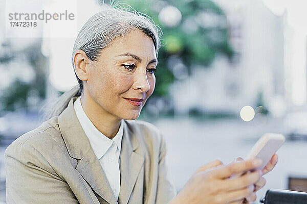 Reife Frau mit grauem Haar  die Textnachrichten über das Smartphone sendet