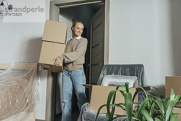 Lächelnde Frau mit Kartons zieht in neue Wohnung um
